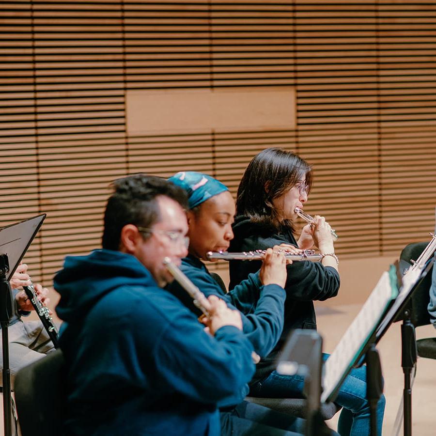 Students rehearse orchestra playing flutes.